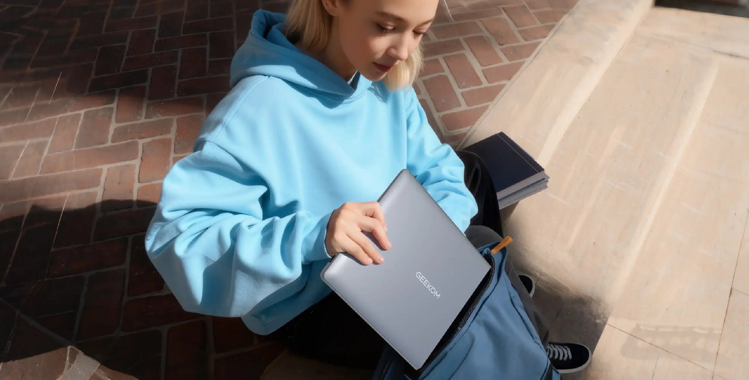 Die Studentin saß auf den Steinstufen und holte ihren Geekbook-Laptop aus ihrer Tasche.